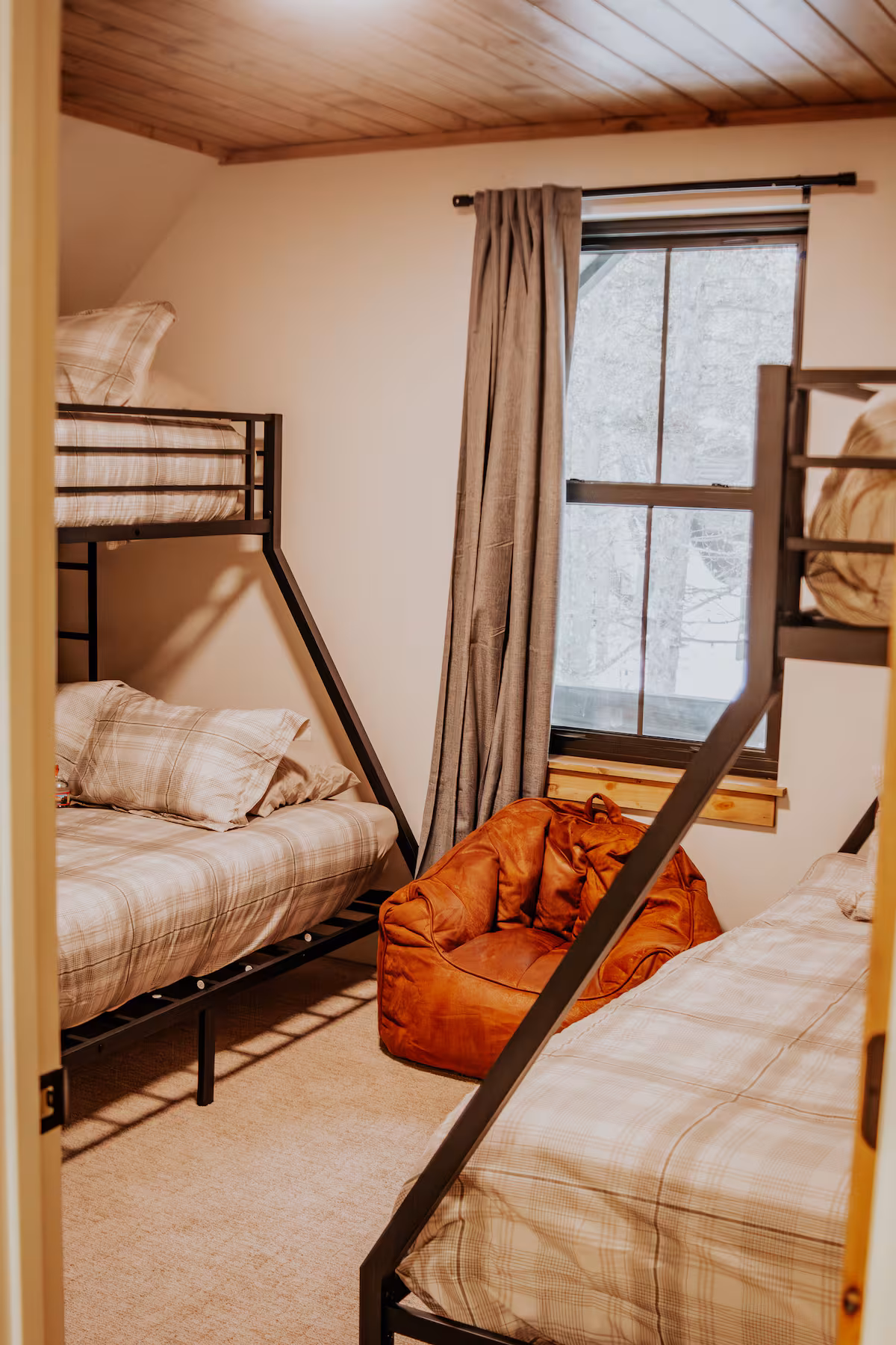 Bunk room with twin-over-full bunks, plaid bedding and a leather bean bag