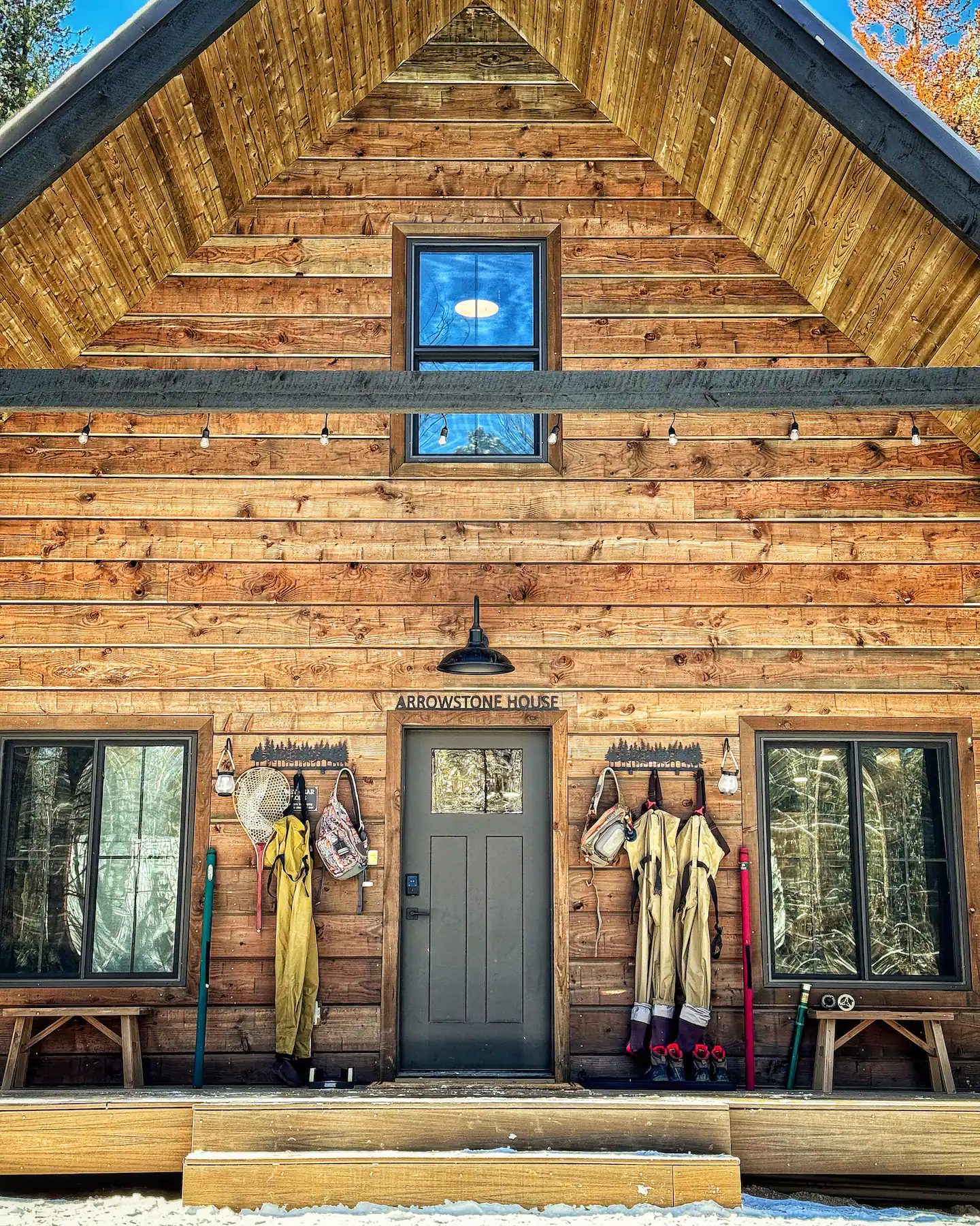 Arrowstone House front gable with waders, nets and fly-fishing gear hung beside the door