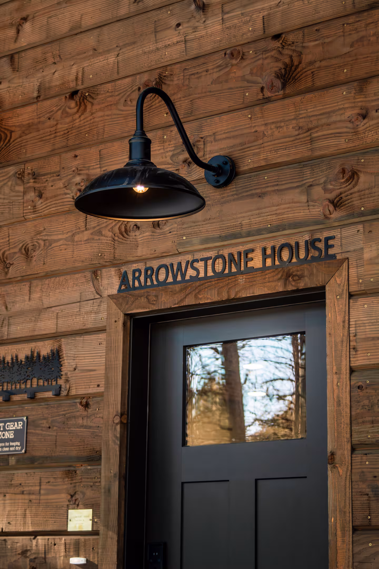 Arrowstone House sign over the front door under a gooseneck lamp